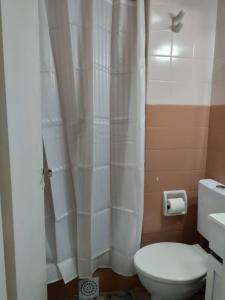 a bathroom with a toilet and a white shower curtain at Luminoso monoambiente con cochera propia dentro del edificio in La Plata +19 photos