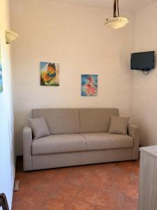 a couch in a living room with three paintings on the wall at Borgo Luce - Rooftop and Rooms in Francavilla Marittima