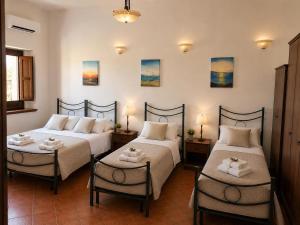 a room with three beds and two tables and two lamps at Borgo Luce - Rooftop and Rooms in Francavilla Marittima