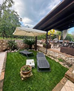 a patio with an umbrella and a lawn with a bench at Il Nido di Zia Mina in Formia