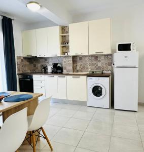 a kitchen with white cabinets and a washer and dryer at Sunny Siviri in Siviri