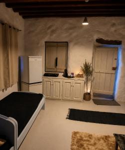 a room with a kitchen with a bed and a refrigerator at Artemis Cottage Authentic Mykonian Stone House near Super Paradise in Super Paradise Beach