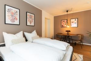 two white beds in a room with a table at Neu & modern - hej homes mit kostenfreiem Parken in Bad Kissingen