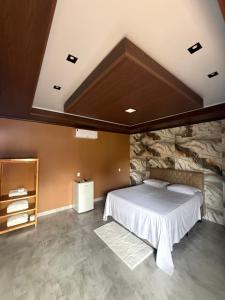 a bedroom with a bed and a stone wall at Pousada Raio de Luz in Pirenópolis