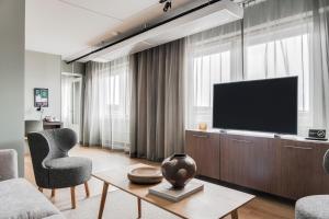 ein Wohnzimmer mit Fernseher, Sofa und Sesseln in der Unterkunft Quality Hotel Luleå in Luleå
