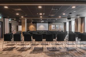 ein Konferenzraum mit schwarzen Stühlen und einem Bildschirm in der Unterkunft Quality Hotel Luleå in Luleå