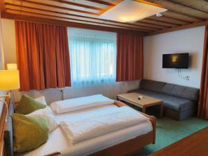 a hotel room with a bed and a couch at Hotel-Pension Birkenhof in Kötschach
