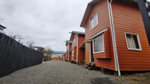 a row of orange homes next to a fence at Cabañas Ohiggins in Dalcahue