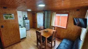 a kitchen and dining room with a wooden table and chairs at Cabañas Ohiggins in Dalcahue