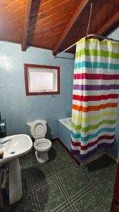 a bathroom with a rainbow shower curtain and a toilet at Cabañas Ohiggins in Dalcahue +15 photos