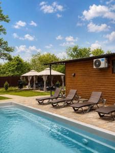 a swimming pool with lounge chairs and a house at Joy WoodRest in Voropayev