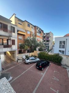 two cars parked in a parking lot in a city at Host Apartments in Shkodër