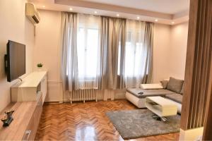 uma sala de estar com um sofá e uma televisão em Bojan Central Apartment em Novi Sad