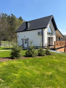 a white house with a black roof and a yard at Polana House in Niedźwiada