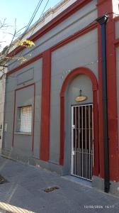 a red and white building with a door at Hospedaje "Doña Tomasa" -A 15 minutos del aeropuerto -Parking in Ezeiza