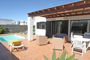 un patio con sillas, una mesa y una piscina en VILLA BERMEJA 10 by Villitas, en Playa Blanca