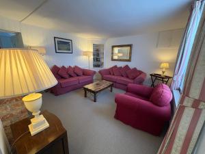 a living room with purple couches and a table at Stunning 3 bedroom 3 bath self catering cottage nr Stonehenge, Salisbury, Longleat, Avebury and Bath, Short walk to lovely village pub in Pewsey