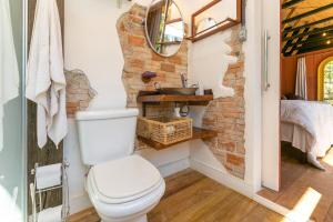 a bathroom with a white toilet and a brick wall at Cabana Paiol de Baixo in Curitiba