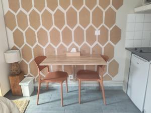 a table and two chairs in a kitchen with a wall at Studio équipé proche Stade de France in Épinay-sur-Seine