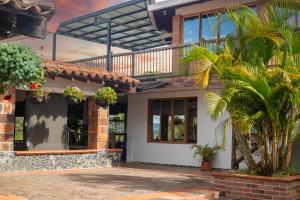 a house with a balcony and palm trees at Hotel Estaciones in Guatapé