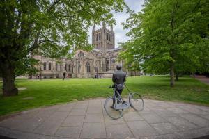 a statue of a man on a bike in front of a cathedral at Characterful Home Steps from Cathedral in Hereford