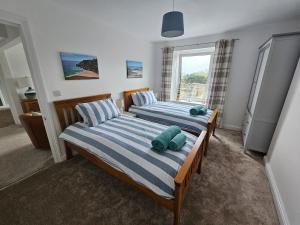 two twin beds in a room with a window at Railway Cottage, Liskeard in Liskeard