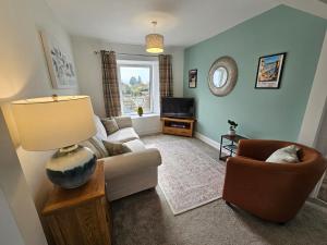 a living room with a couch and a table with a lamp at Railway Cottage, Liskeard in Liskeard