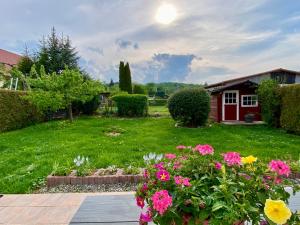 a garden with pink flowers and a red house at Ferienhaus Sonnenblick Wernigerode in Wernigerode