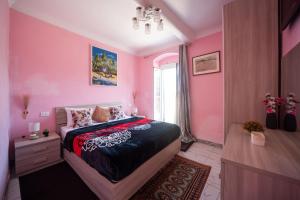 a pink bedroom with a bed and a window at zahira in Biassa