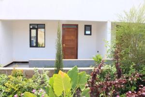 a house with a wooden door in a garden at Kithumulani Resort in Tiva