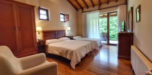 a bedroom with two beds and a chair and a window at Hotel Palación de Toñanes in Toñanes