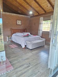 a bedroom with a bed in a brick wall at Chalé Água Santa in São Thomé das Letras