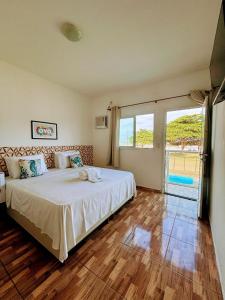a bedroom with a large bed and a large window at Pousada Sol & Mar Jacaraìpe ES in Serra