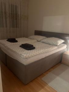 a bed with two black hats on top of it at Iris Apartment in Dunajská Streda