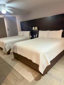two beds sitting next to each other in a bedroom at Nueva Vizcaya & Suites in Hidalgo del Parral