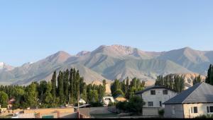 a town with mountains in the background with houses and trees at Zhailoo Guest House Kochkor in Kochkorka