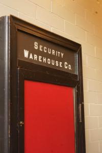 a sign that reads security warehouse co next to a red door at The Grey Cannon Guest House in Saint Cloud