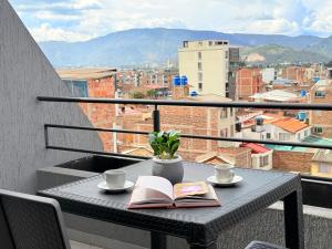 a table with two books and coffee cups on a balcony at Exclusivo Apartamento Céntrico con Terraza Privada in Sogamoso