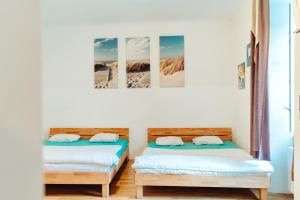 two beds in a room with two pictures on the wall at City Center Studio in Graz