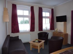 a living room with a couch and two windows at Pension Märkische Bauernstube in Schorfheide