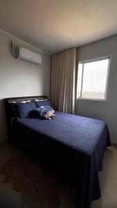 a bedroom with a bed with a blue comforter and a window at Brisas do Lago 2 Quartos in Palmas