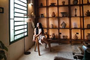 a woman sitting on a chair in a room with a lamp at Kuka y Milpa in Mérida