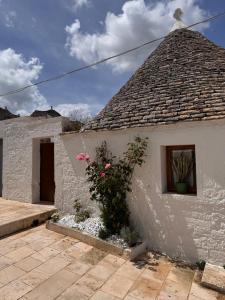 a white building with a roof with a window and flowers at Trullidea in Alberobello