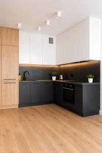 a kitchen with white cabinets and black counter tops at Slovianka Residence - strefa spa oraz darmowy parking! in Łódź
