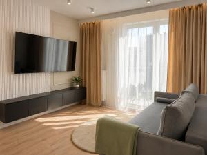 a living room with a couch and a flat screen tv at Slovianka Residence - strefa spa oraz darmowy parking! in Łódź