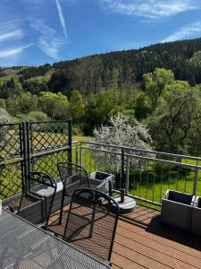 a deck with two chairs and a fence and trees at Chalet Relax in Birresborn