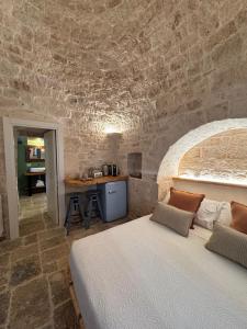 a bedroom with a bed and a stone wall at Trullidea in Alberobello