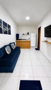 a living room with a blue couch and a kitchen at Casa no centro de Ponta de Pedras - Casa da Baleia VILA ORION in Goiana