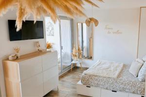 a bedroom with a bed and a dresser with a tv at Sable & Pampas - Meublé de Tourisme 5 étoiles - Vue Panoramique & Terrasse - Climatisation - Plage à 200m in Carnon-Plage
