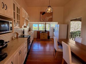 a kitchen with white cabinets and a table with chairs at Kilkivan Homestead in Kilkivan +6 photos